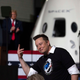 Elon Musk takes a bow in front of a SpaceX prop rocket. Former President Donald Trump claps in the background.